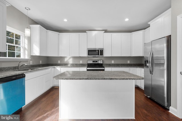 kitchen with sink, a center island, dark wood-type flooring, and appliances with stainless steel finishes