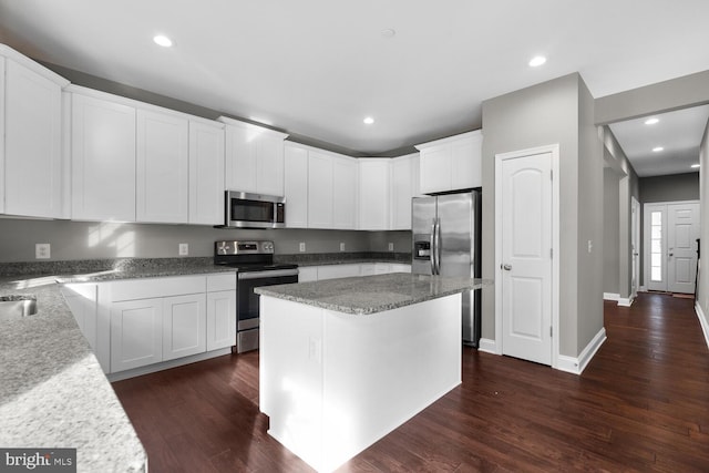 kitchen featuring white cabinets, a kitchen island, dark wood-type flooring, and appliances with stainless steel finishes