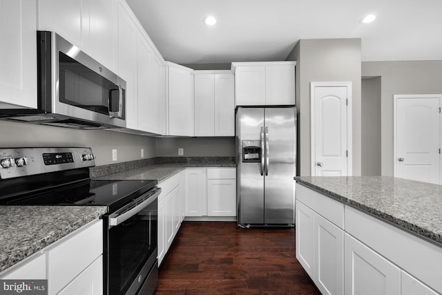 kitchen featuring white cabinets, appliances with stainless steel finishes, dark hardwood / wood-style floors, and light stone counters