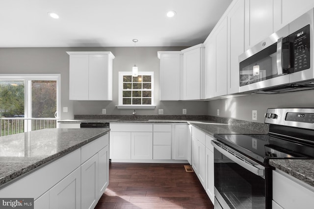 kitchen featuring dark stone countertops, white cabinetry, dark wood-type flooring, and stainless steel appliances