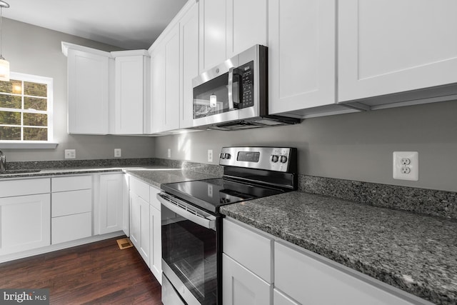 kitchen with white cabinetry, sink, dark hardwood / wood-style flooring, dark stone countertops, and appliances with stainless steel finishes