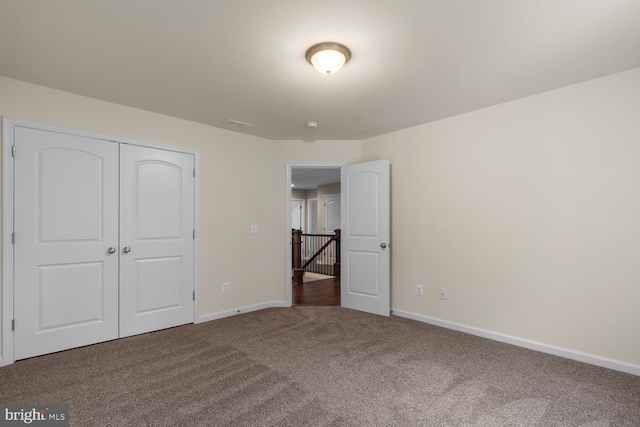 unfurnished bedroom with dark carpet and a closet