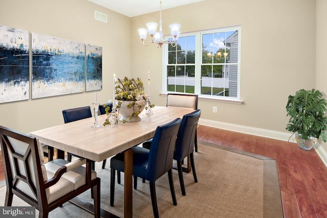 dining space with hardwood / wood-style floors and a notable chandelier