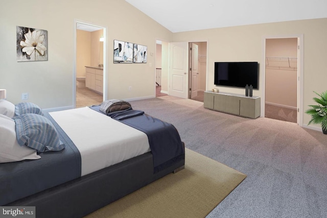 bedroom with a spacious closet, ensuite bathroom, light colored carpet, lofted ceiling, and a closet