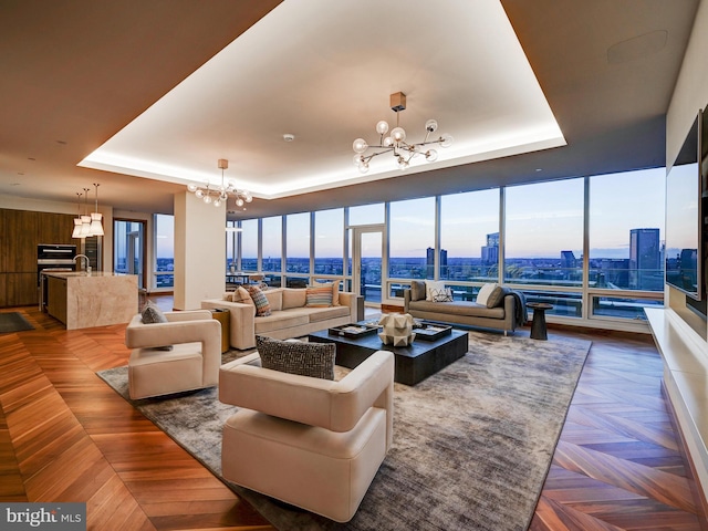 living room with a raised ceiling, dark parquet flooring, wooden walls, and a chandelier