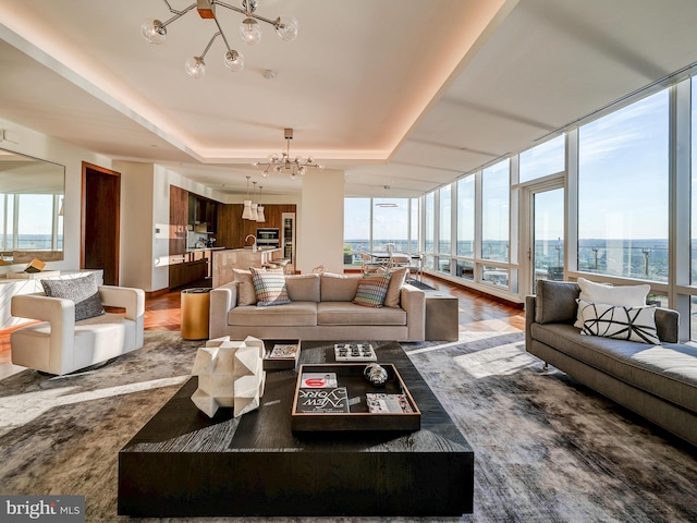 living room with hardwood / wood-style flooring, floor to ceiling windows, a raised ceiling, and a chandelier