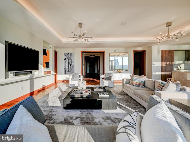 living room featuring a raised ceiling, an inviting chandelier, and hardwood / wood-style floors