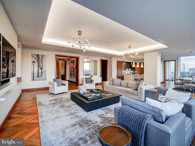 living room featuring a raised ceiling, parquet flooring, and an inviting chandelier