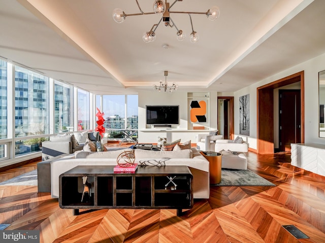 living room with parquet flooring, a tray ceiling, and an inviting chandelier