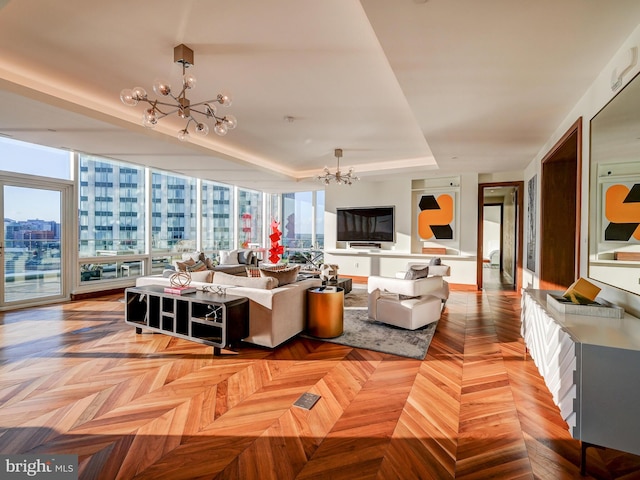 living room featuring plenty of natural light, light parquet flooring, and an inviting chandelier