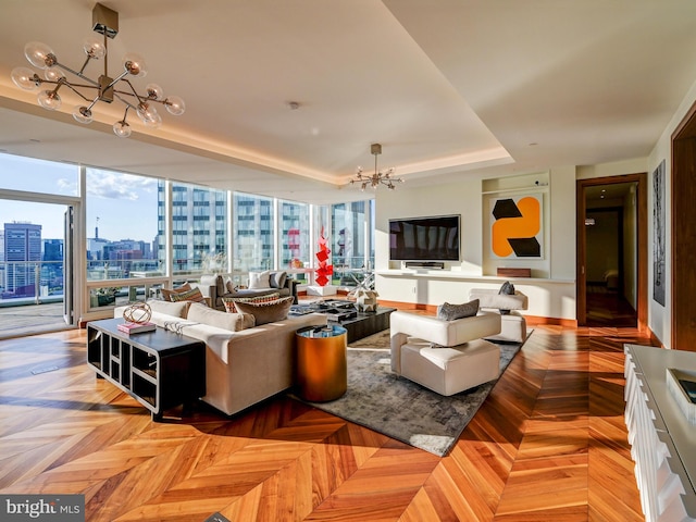 living room featuring light parquet flooring, a raised ceiling, and a notable chandelier