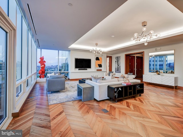 living room featuring plenty of natural light, light parquet flooring, and a chandelier