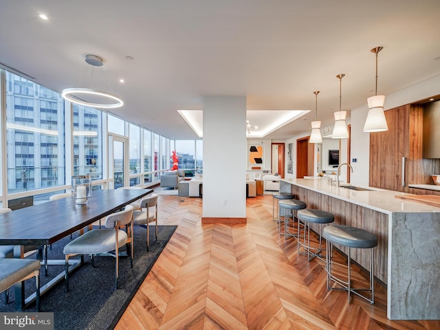 dining space with a wall of windows, sink, and light parquet flooring