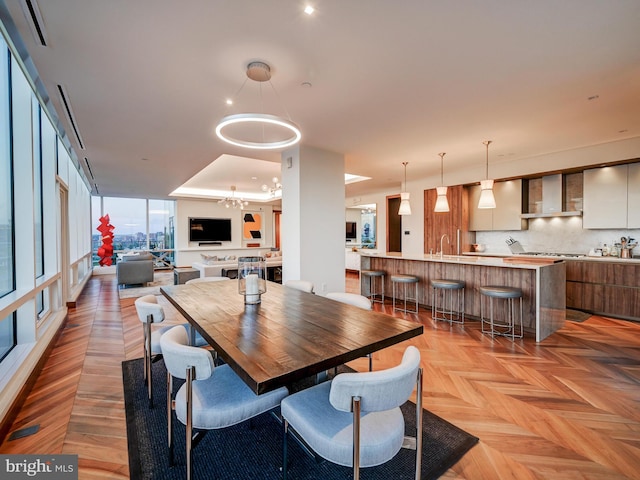 dining area with sink, light parquet flooring, and a notable chandelier