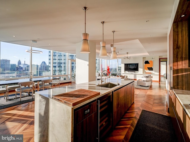 kitchen featuring a center island with sink, light parquet floors, hanging light fixtures, and sink