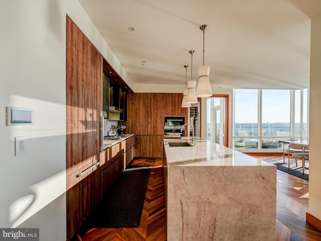 kitchen featuring light stone countertops, sink, stainless steel appliances, dark parquet floors, and decorative light fixtures