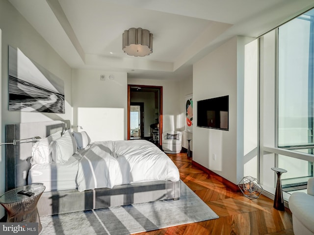 bedroom with dark parquet flooring and a tray ceiling