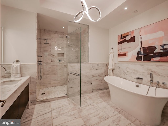 bathroom featuring vanity, independent shower and bath, and tile walls