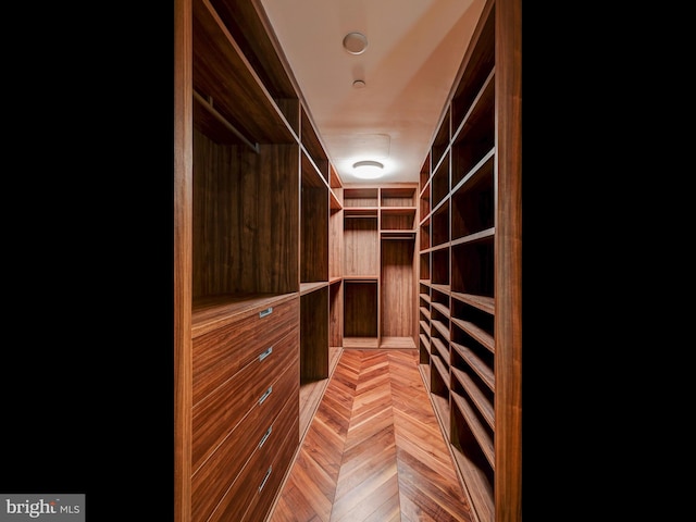 walk in closet with light parquet floors