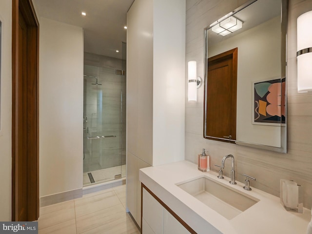 bathroom with tile patterned floors, vanity, tile walls, and walk in shower