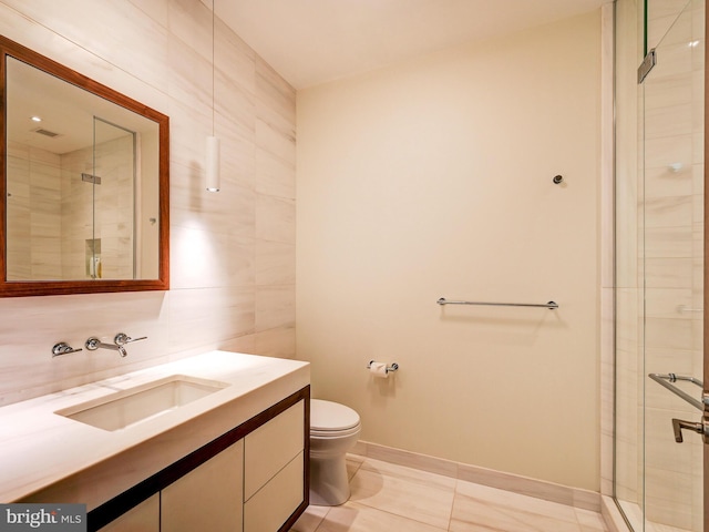 bathroom featuring tile patterned floors, an enclosed shower, toilet, vanity, and tile walls