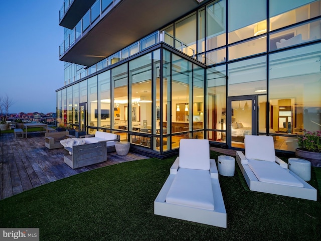 deck at dusk with a lawn and an outdoor living space