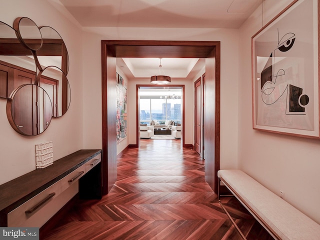 hallway with a tray ceiling and dark parquet flooring