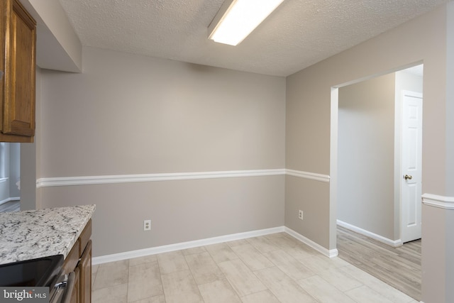 kitchen featuring light stone counters, light hardwood / wood-style flooring, a textured ceiling, and range