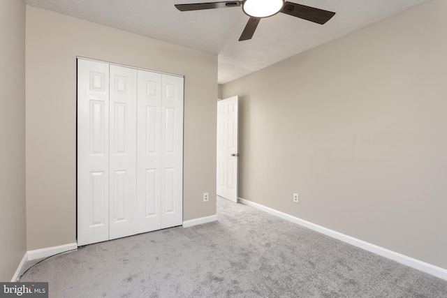 unfurnished bedroom with light carpet, a textured ceiling, a closet, and ceiling fan