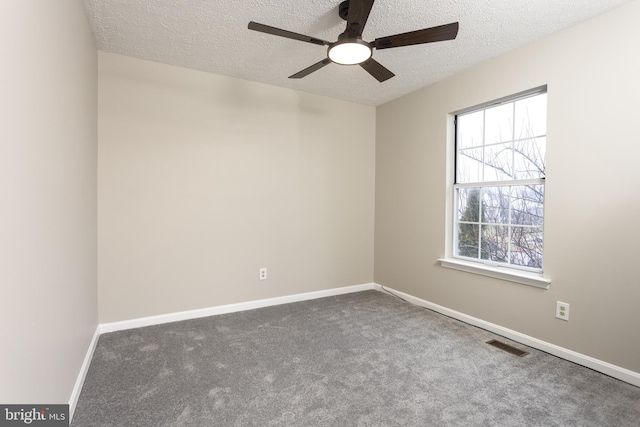 empty room with ceiling fan, dark carpet, and a textured ceiling