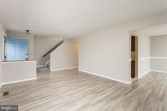 unfurnished living room with light hardwood / wood-style floors and a textured ceiling