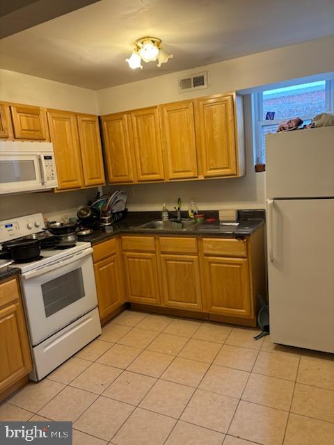 kitchen featuring sink, light tile patterned floors, and white appliances