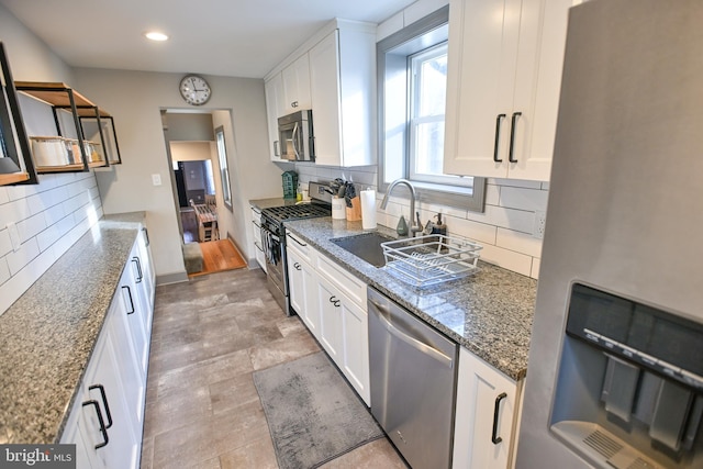 kitchen with dark stone countertops, decorative backsplash, white cabinets, and appliances with stainless steel finishes