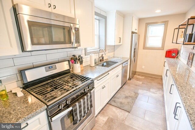 kitchen featuring sink, stainless steel appliances, light stone counters, backsplash, and white cabinets