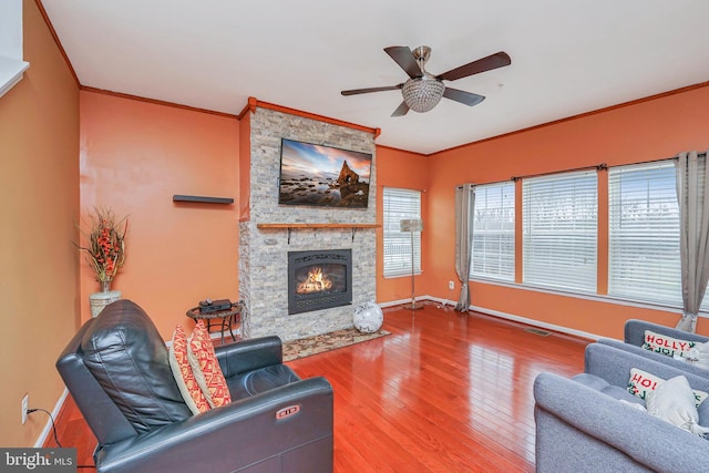 living room featuring a fireplace, crown molding, hardwood / wood-style floors, and ceiling fan