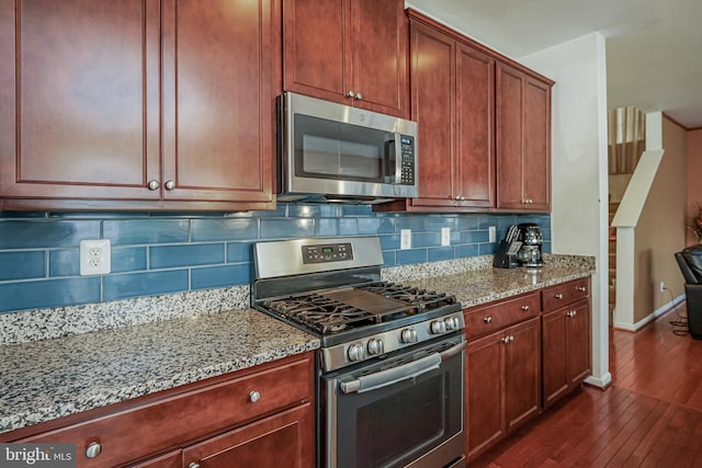 kitchen featuring backsplash, light stone countertops, dark wood-type flooring, and stainless steel appliances