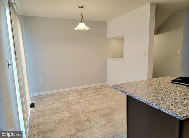 kitchen featuring decorative light fixtures, light stone counters, and kitchen peninsula