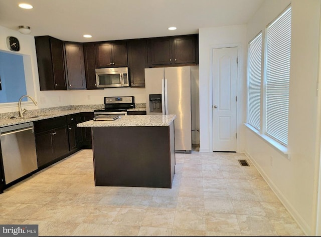 kitchen featuring sink, a kitchen island, dark brown cabinets, and appliances with stainless steel finishes