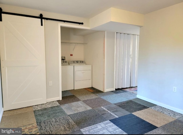 washroom featuring a barn door, dark carpet, and washer and clothes dryer