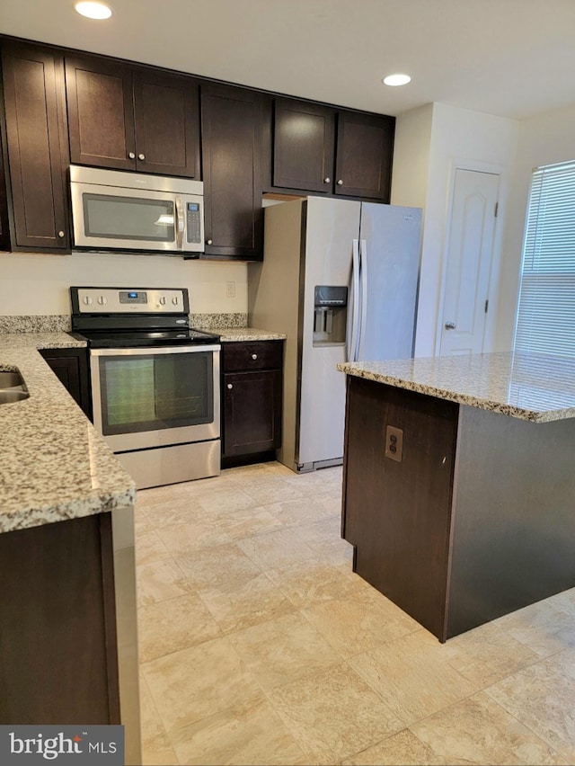 kitchen with light stone counters, dark brown cabinets, and stainless steel appliances