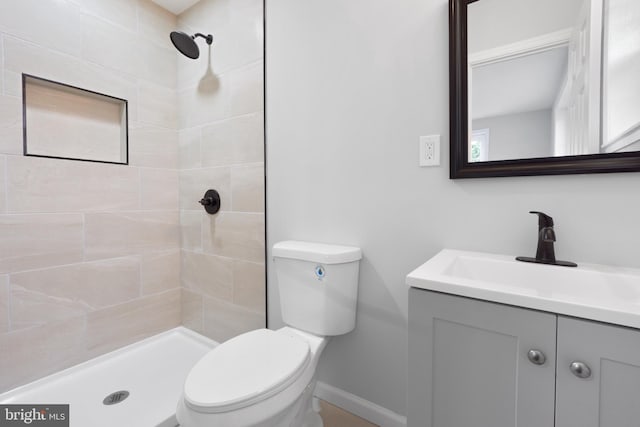 bathroom featuring tiled shower, vanity, and toilet