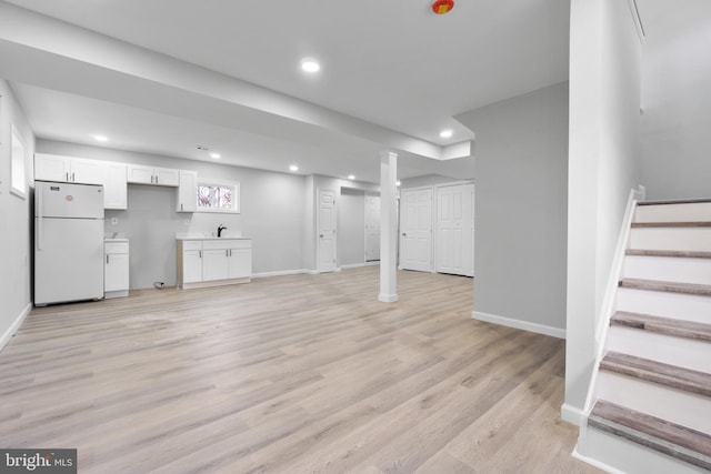 basement with sink, light hardwood / wood-style floors, and white refrigerator