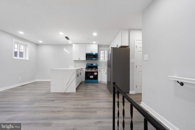 kitchen featuring white cabinetry, stainless steel appliances, light stone counters, light hardwood / wood-style floors, and decorative light fixtures