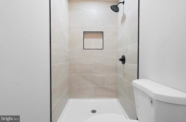 bathroom featuring a tile shower and toilet