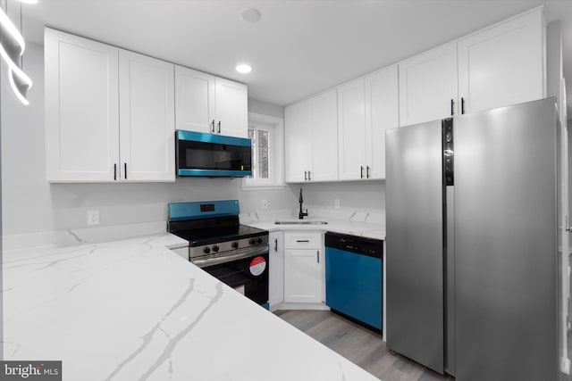 kitchen with sink, light wood-type flooring, light stone counters, white cabinetry, and stainless steel appliances