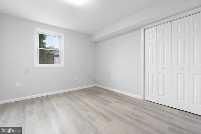 unfurnished bedroom with light hardwood / wood-style flooring and a closet