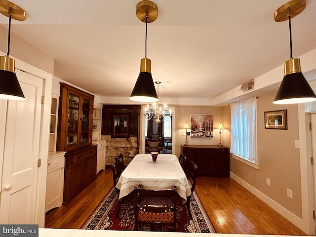 dining space with dark hardwood / wood-style floors and a notable chandelier