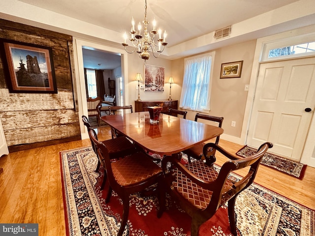 dining room with light wood-type flooring, plenty of natural light, and a notable chandelier