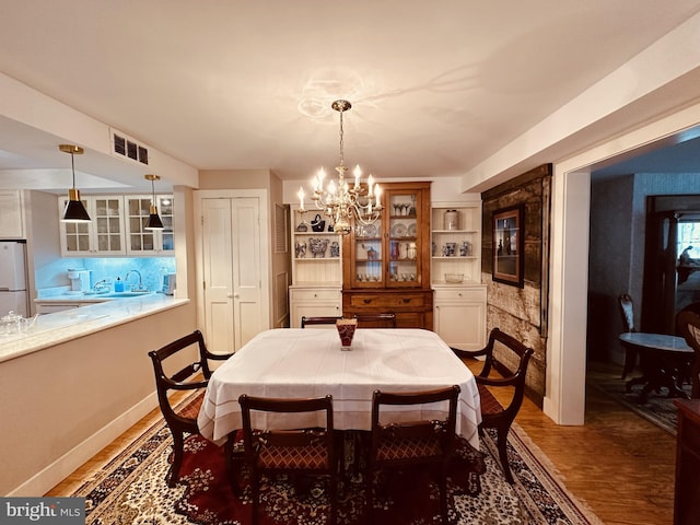 dining area featuring sink, a chandelier, and hardwood / wood-style flooring