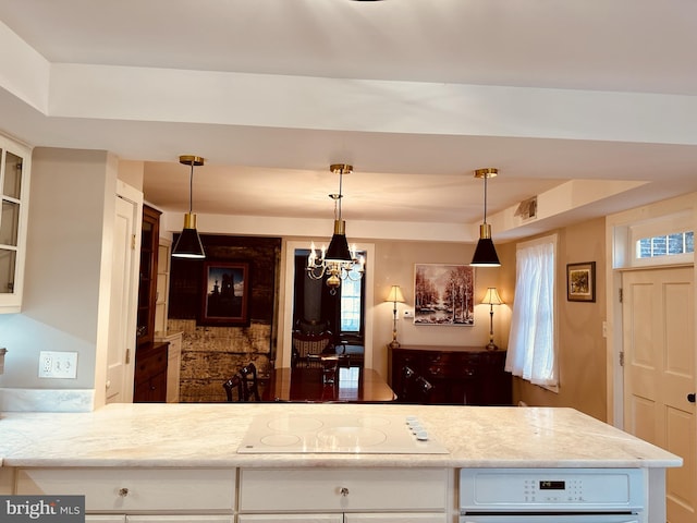 kitchen with electric cooktop, plenty of natural light, white cabinets, and pendant lighting